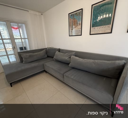 ספה אפורה בחדר עם פוסטרים על הקיר